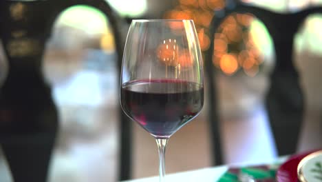 an orbital shot captures the allure of a red wine glass against a mesmerizing bokeh backdrop, a toast to sophistication