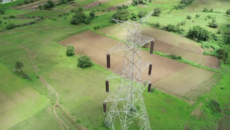 high voltage overhead transmission lines being placed in rural areas of india - aerial drone footage - electricity pylons and high voltage power line