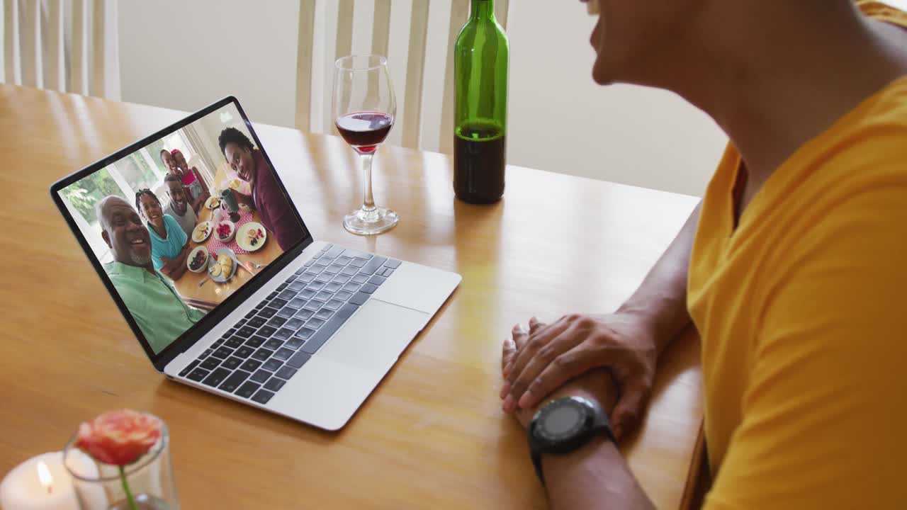 Mid section of african american man talking on video call on laptop at home