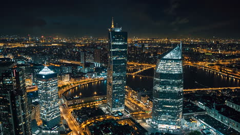 nighttime aerial view of a modern cityscape with illuminated skyscrapers and a river