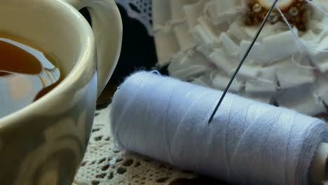 cierre de un paquete de hilo y una aguja en una bandeja con una taza de té