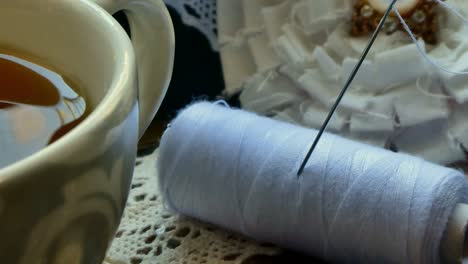 close up of a yarn package and a needle in a tray with a cup of tea