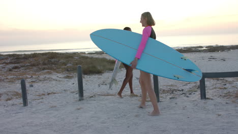 Surfer-walks-towards-the-ocean-at-sunset,-with-copy-space