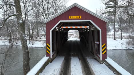 aerial establishing shot of a traditional covered bridge over a stream