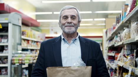 hombre maduro con bolsa de papel en el supermercado