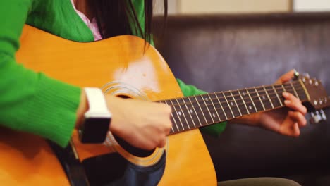 woman playing guitar in living room