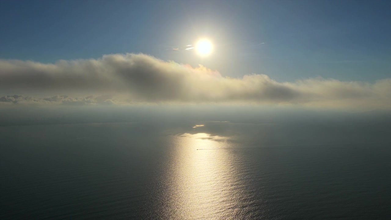 Solen kaster en lys refleksion på havet, med skyer, der driver hen over himlen. Ideel til fredfyldte eller stemningsfulde projekter.