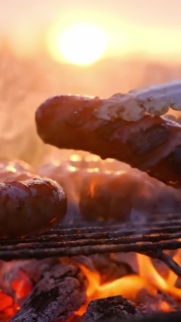 Grigliare salsicce al tramonto: un delizioso banchetto con fumo e fiamme, perfetto per riunioni all'aperto e delizie culinarie.