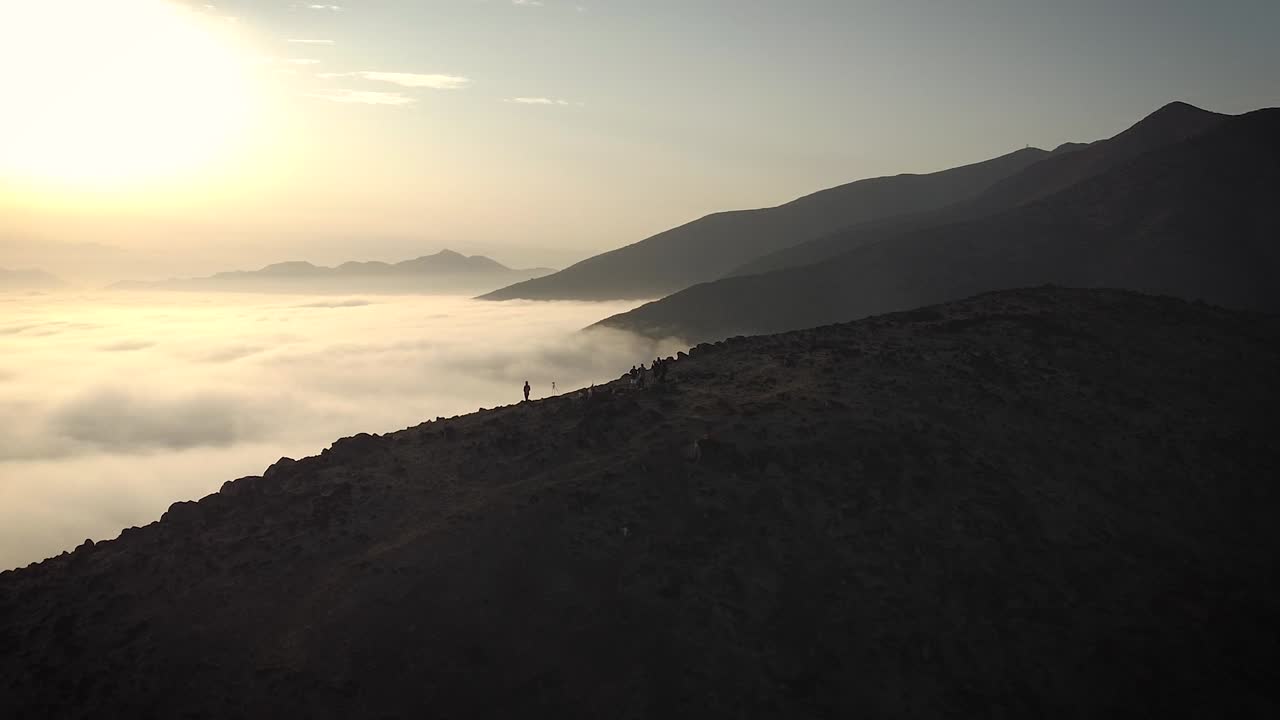 Ripresa aerea panoramica con drone di escursionisti sulle montagne sopra le nuvole all'alba a Lima, Perù.
