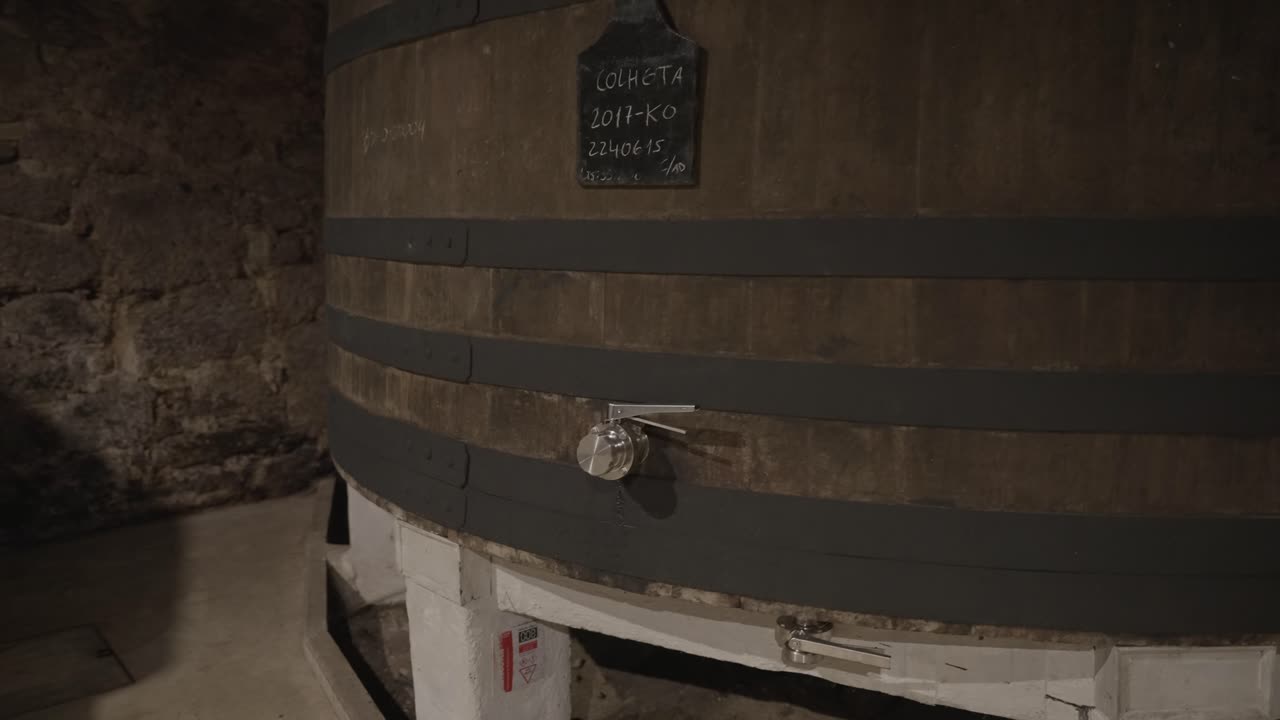 Primo piano di botte di vino in quercia con rubinetto in metallo in cantina di invecchiamento in pietra