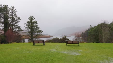 benches on green grass overlooking misty lake landscape in ireland