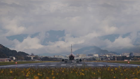 airplane taking off from runway with mountains in background