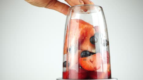 red fruit and berries in a blender churned up to a pulp ready for a healthy smoothie