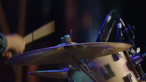 Closeup-of-drum-set-on-stage,-drummer-playing-in-night-performance