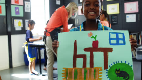 Portrait-of-happy-girl-showing-her-painting-in-drawing-class