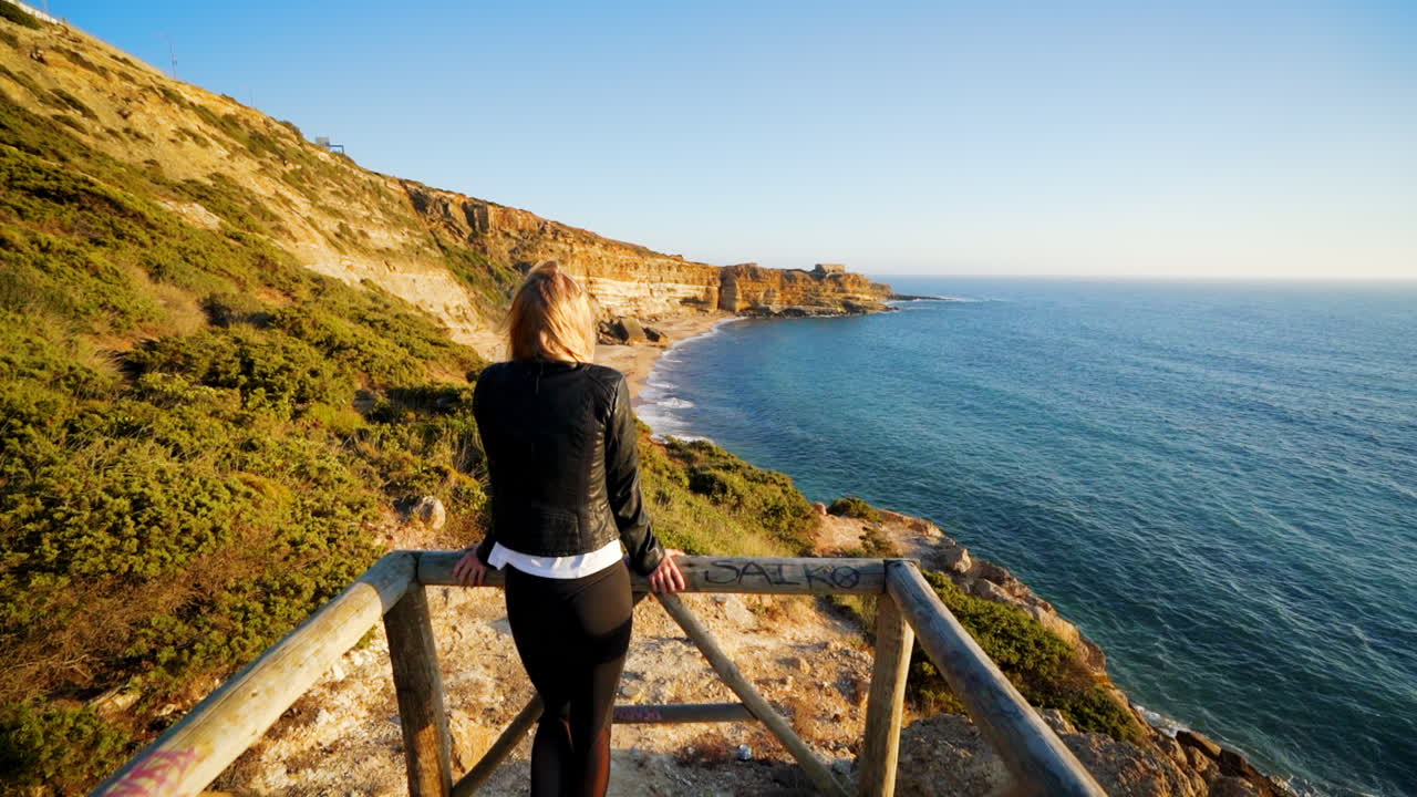 una chica camina hacia la playa de lisboa, portugal