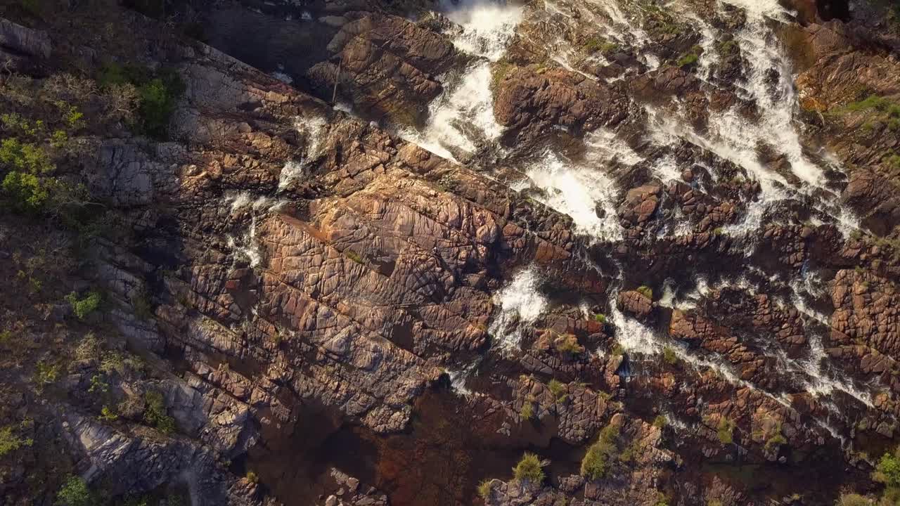 Bird's eye view drone shot flying forward, unveiling the full extent and power of Couros Waterfall, Chapada dos Veadeiros, Goiás, Brazil