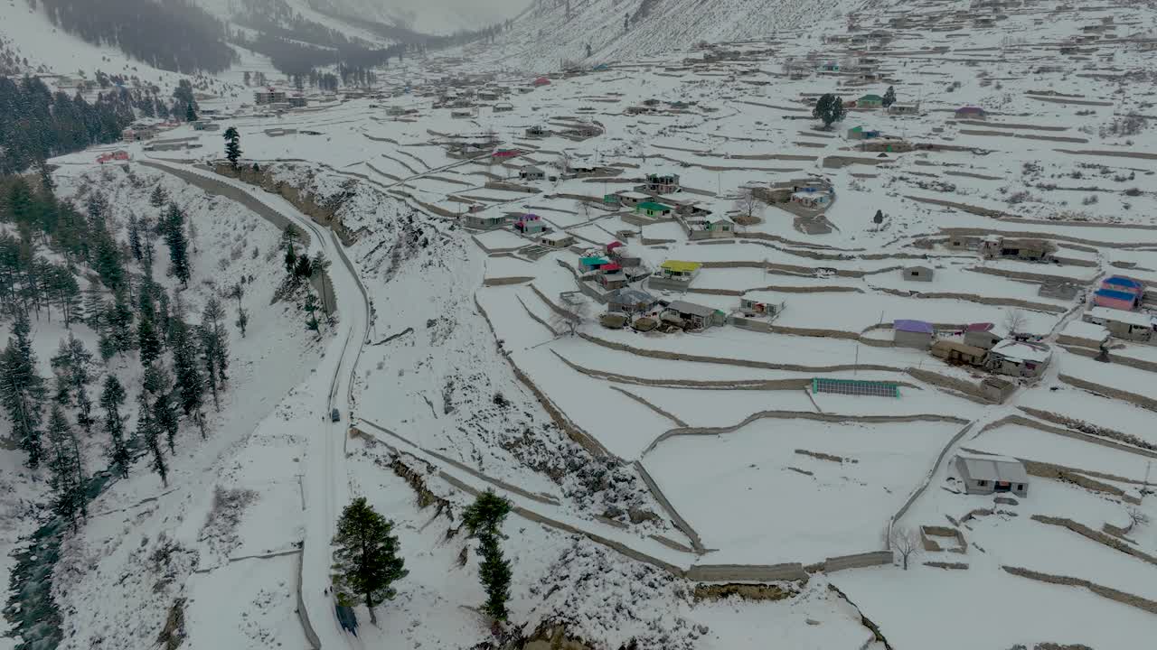 imágenes de drones volando sobre pueblos y casas coloridas sobre el valle de naltar en gilgit pakistán en invierno cubierto de nieve