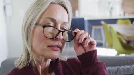 primer plano de una mujer mayor caucásica pensativa con gafas sentada en el sofá en casa