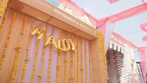 disparo de ángulo bajo de mano de la pared decorada con globos escribiendo haldi, boda india