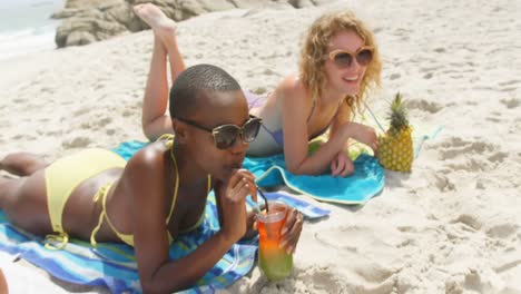 Front-view-of-mixed-race-female-friends-drinking-cocktail-drinks-on-the-beach-4k