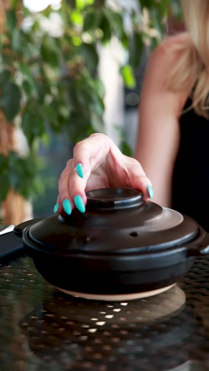 mujer comiendo sopa en una olla de cerámica