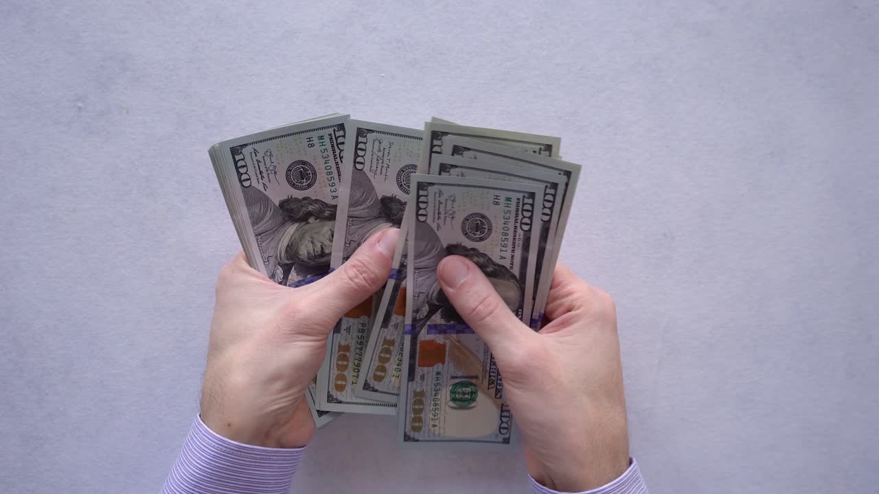 manos del hombre de negocios contando un montón de nuevos billetes de cien dólares