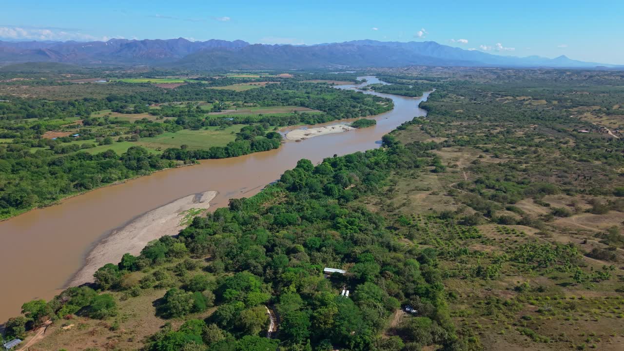 The drone floats above dense green vegetation and flowing waterways, showcasing layers of trees and fertile land. A calm, cinematic aerial capturing the richness and life of Colombia’s lush landscapes