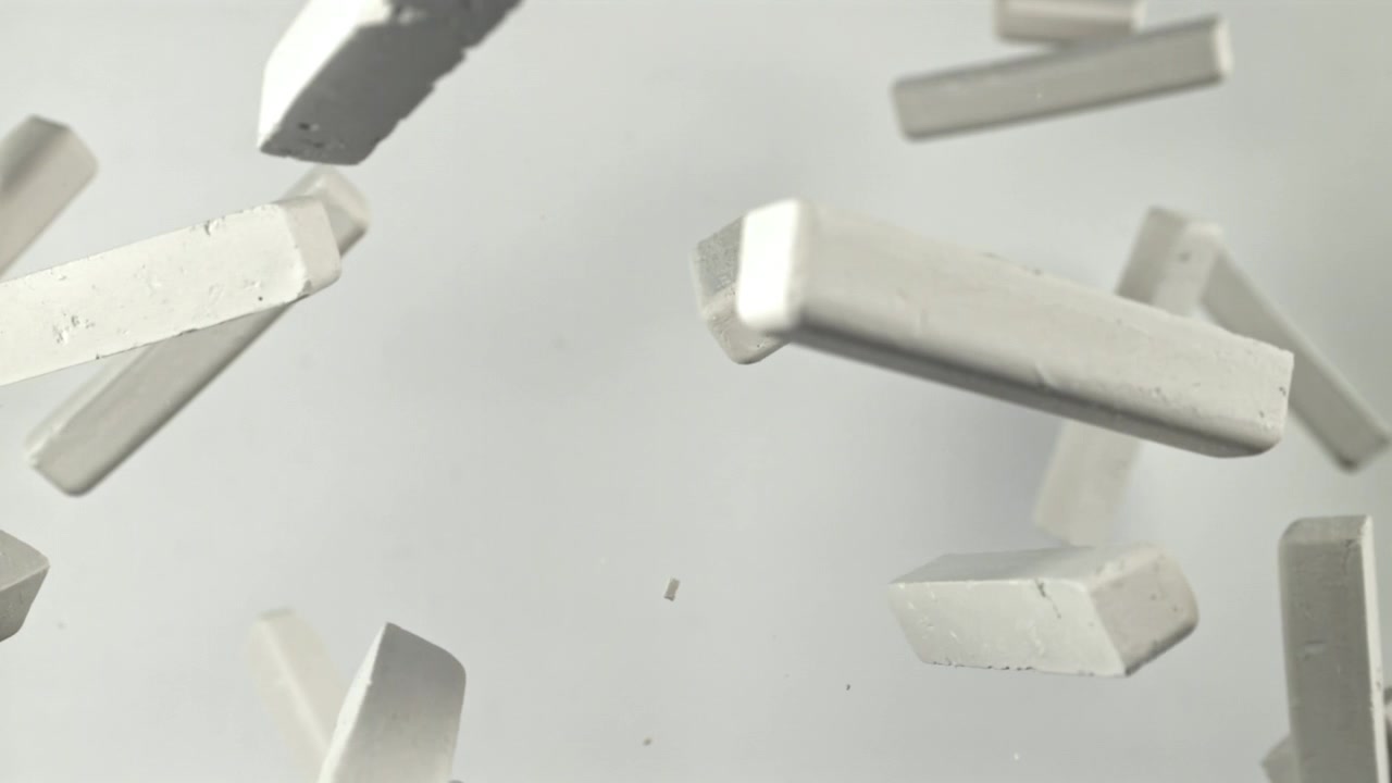 Pezzi di gesso bianco che fluttuano al rallentatore su uno sfondo chiaro.