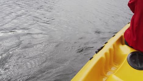 caucasian woman having a good time on a trip to the mountains, kayaking on a lake, holding a paddle