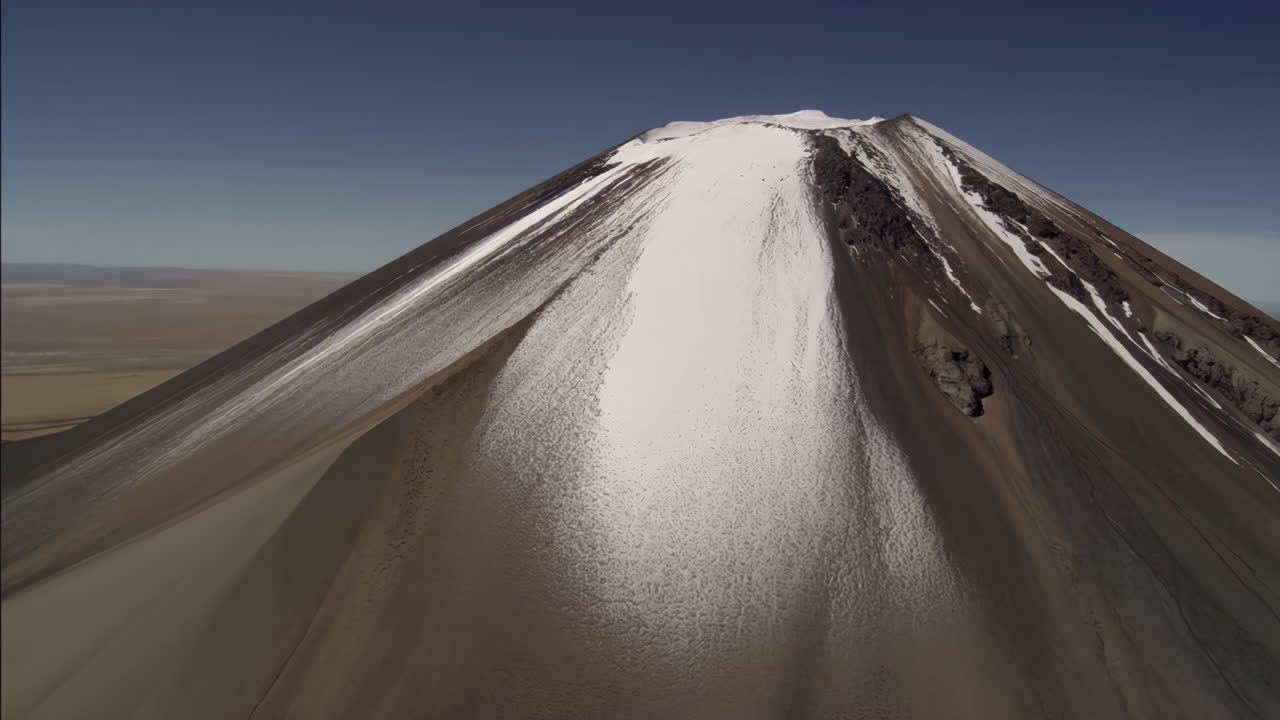 A majestic snow-capped volcano under a clear blue sky