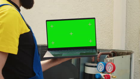 technician with green screen laptop