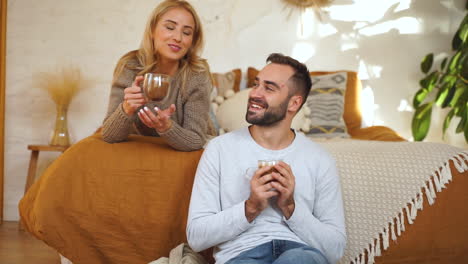 Una-Pareja-Encantadora-Tiene-Una-Conversación-Romántica-Y-Una-Taza-De-Chocolate-Caliente-Abrazándose-En-La-Cama-En-Un-Día-De-Invierno