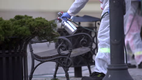 bombero rociando banco público con desinfectante en la plaza principal de la ciudad