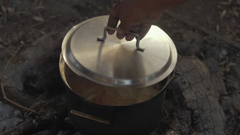 refugiado levanta la tapa cocinando comida campo de refugiados