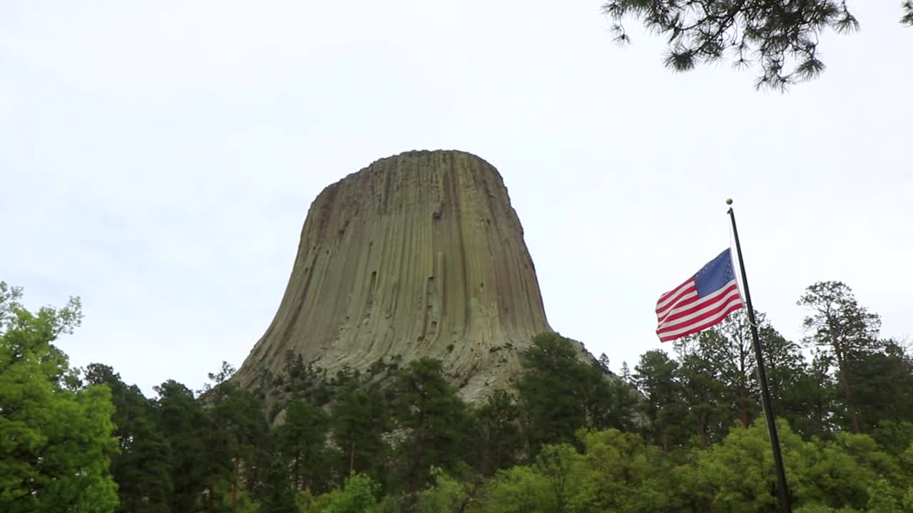 Video approaching Devils Tower in Wyoming with an American flag waving in the scene