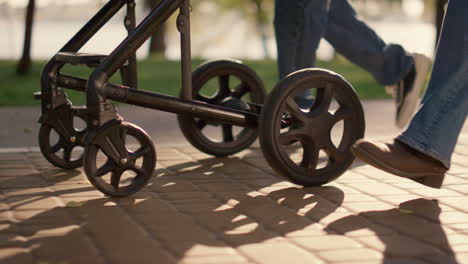 parent legs carriage wheels rolling walkway closeup. loving parenthood concept.