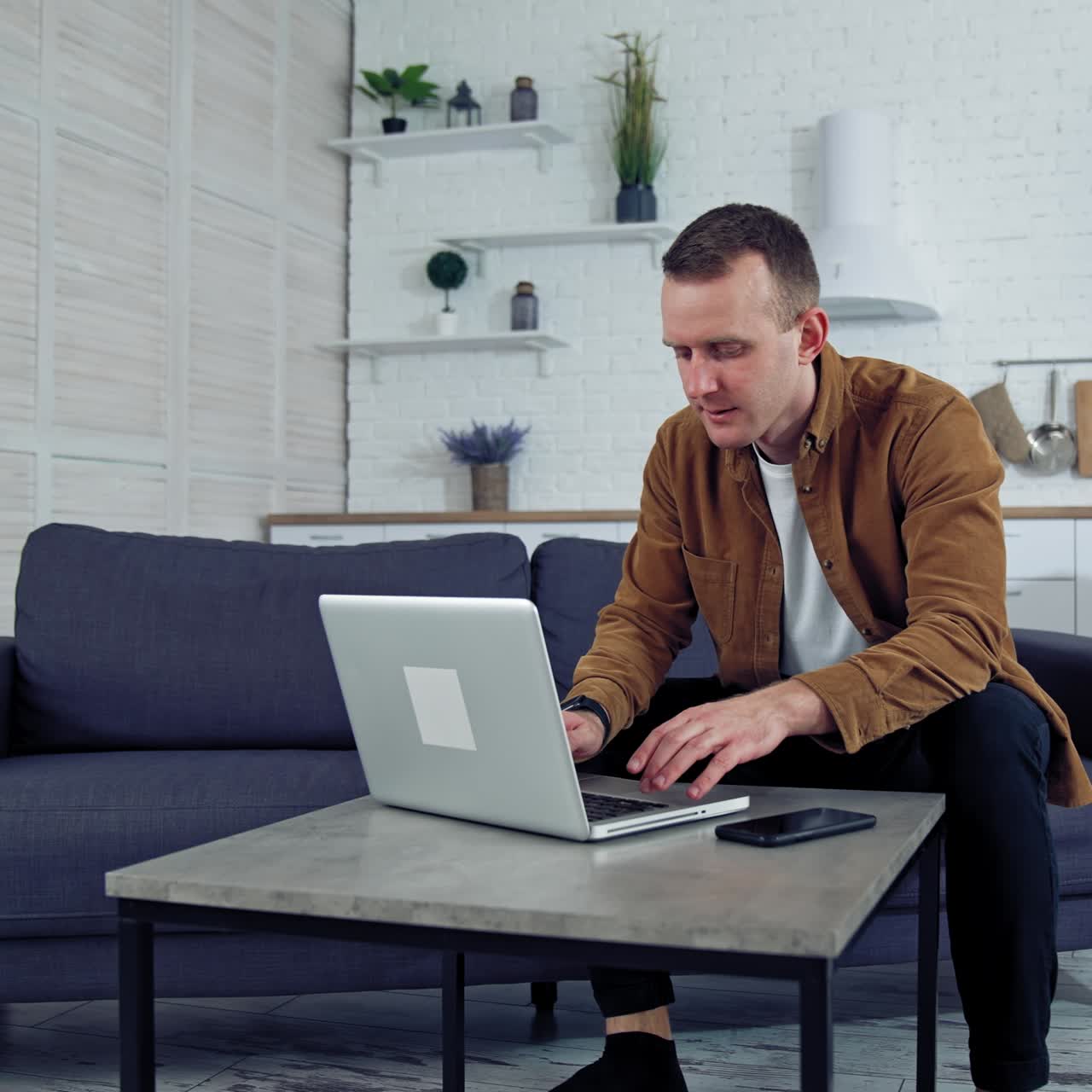 Young male working from home. Portrait of freelancer man working on laptop at home sitting on couch. Quarantine remote work