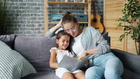 mother and daughter reading a book on the sofa