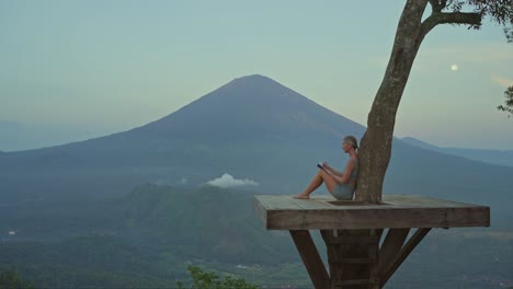 woman writing emotions in journal at tropical viewpoint, mental health concept