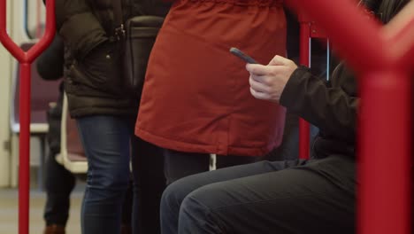 a man on the subway is texting on his cell phone