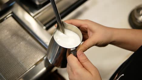 barista making hot milk foam by using the heat from the machine