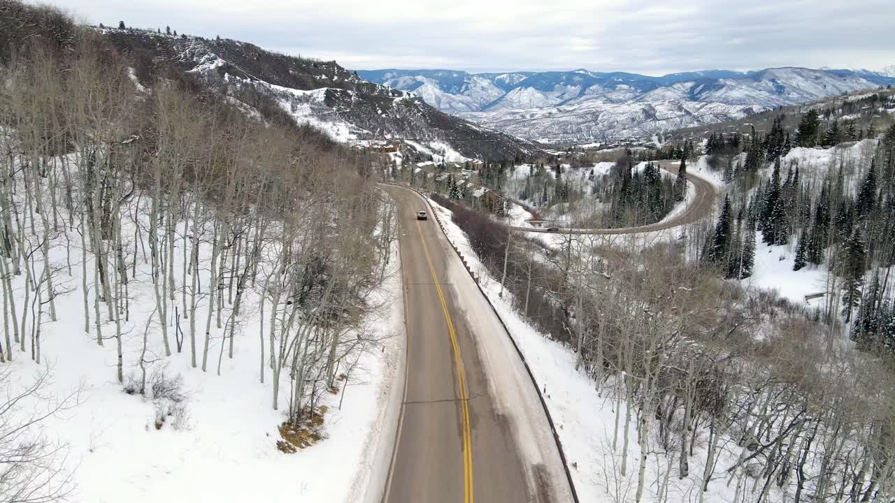 Aerial drone shot of car driving on road in Aspen, Colorado.