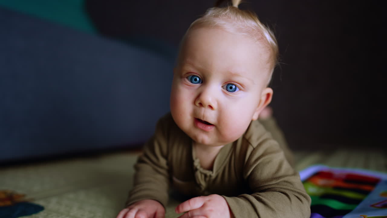 Bedårende kaukasisk blond baby krabber på gulvet. Søtt blåøyd barn prøver å nå kameraet.