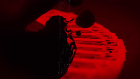 animación de forma negra y arañazos que se mueven sobre cartas de juego rojas en fondo oscuro