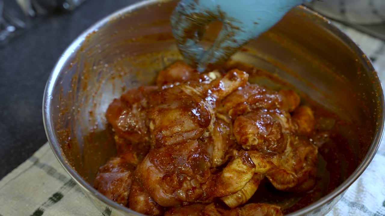un chef, con guantes, marinando hábilmente el pollo con salsa y especias