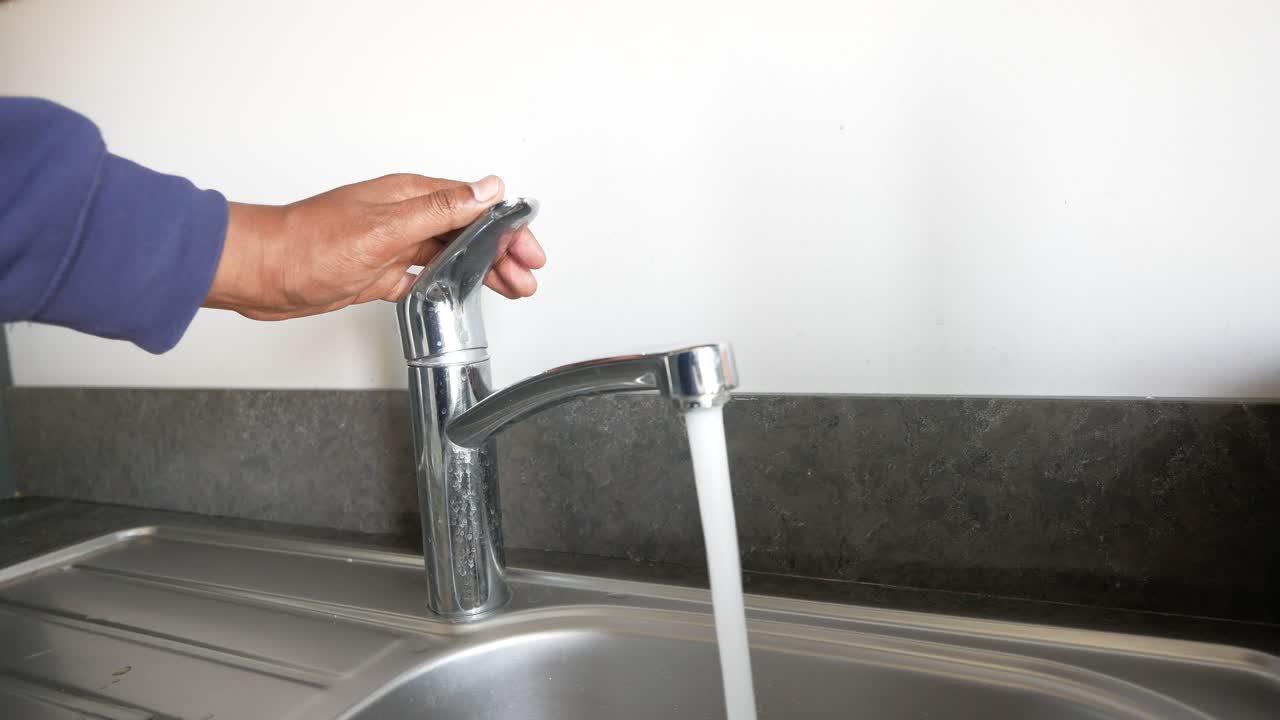 persona que enciende un grifo de la cocina
