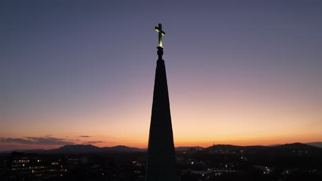 aerial shot of cross on top of church tower at dusk. sunset time with moon at night sky. small american town in virginia. orbit shot of silhouette.