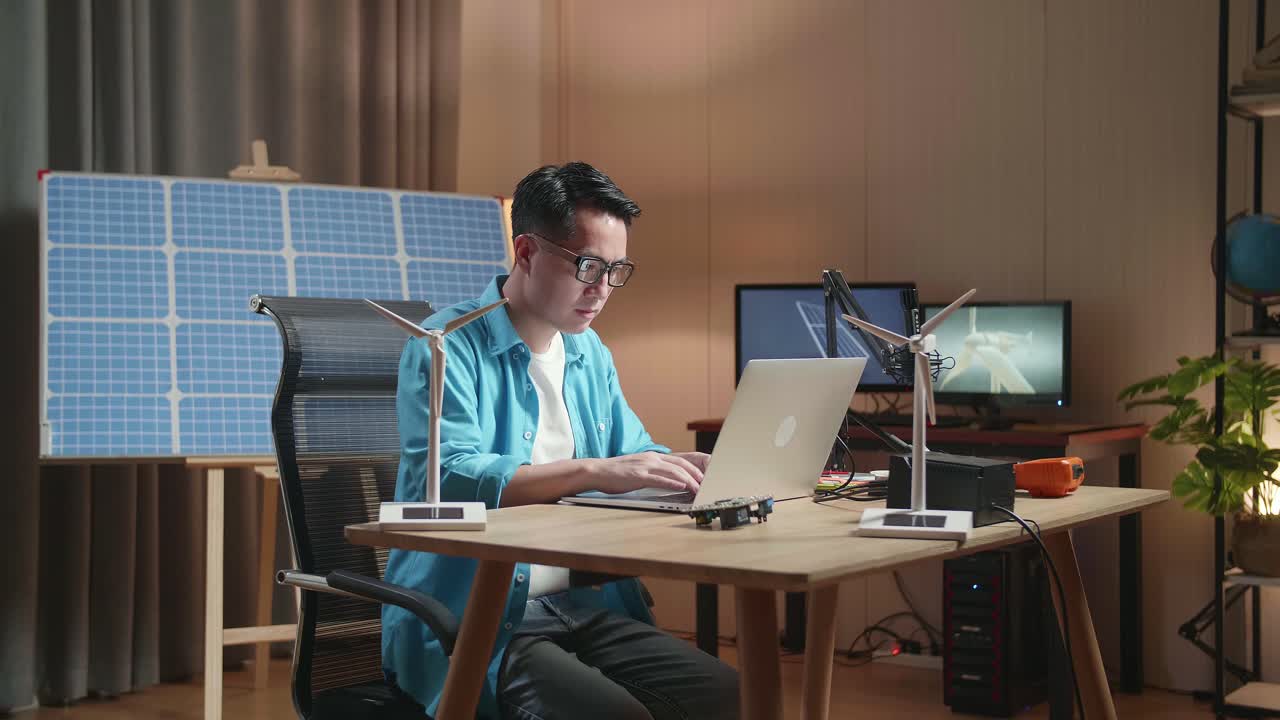 사무실 에서 노트북 에 타이핑 하는 태양 전지 앞 에 앉아 있는 아시아인