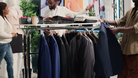 man closely looking at blazers in mall